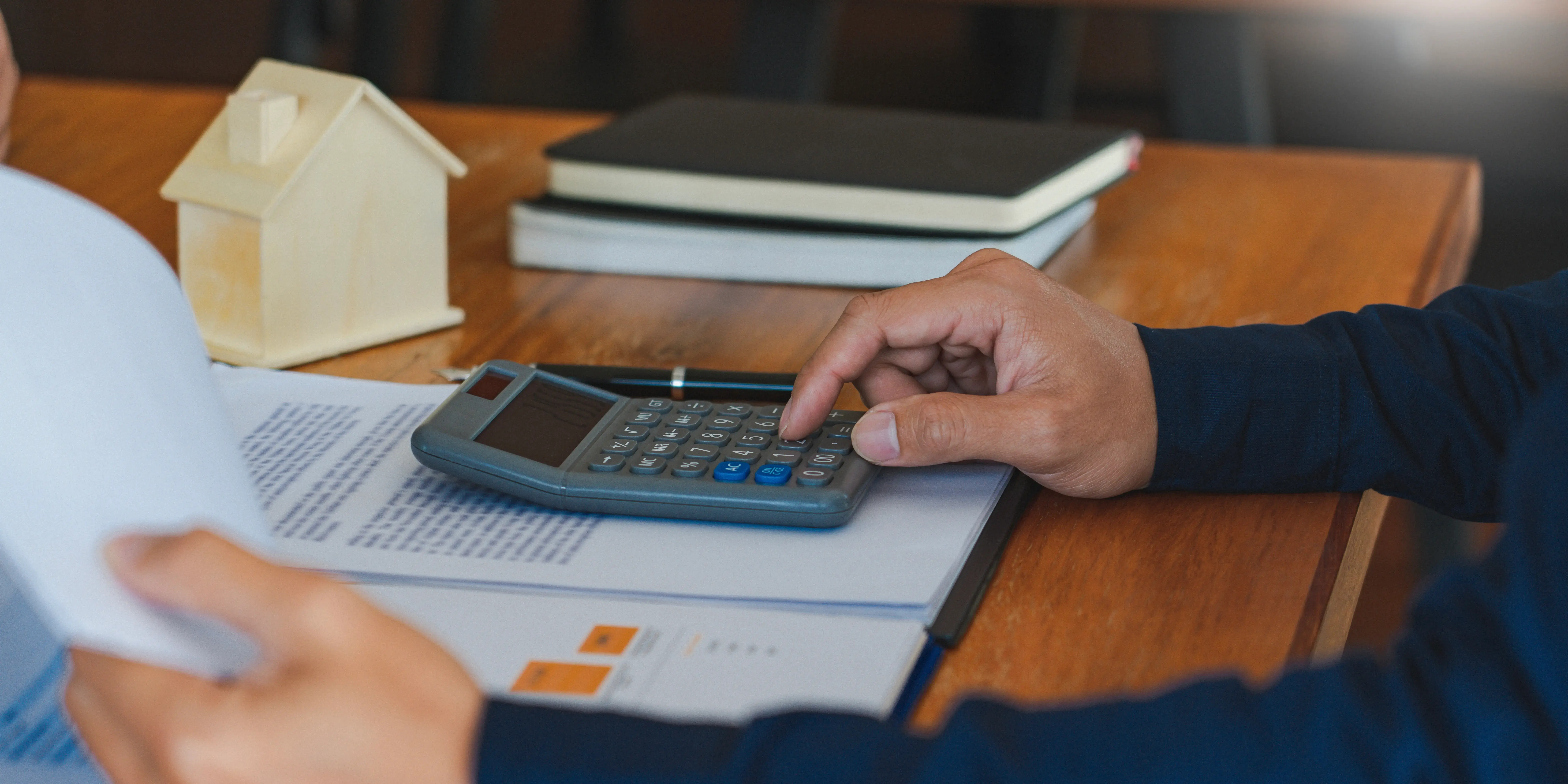 Hombre con una calculadora calculando el presupuesto y gastos asociados para comprar una casa