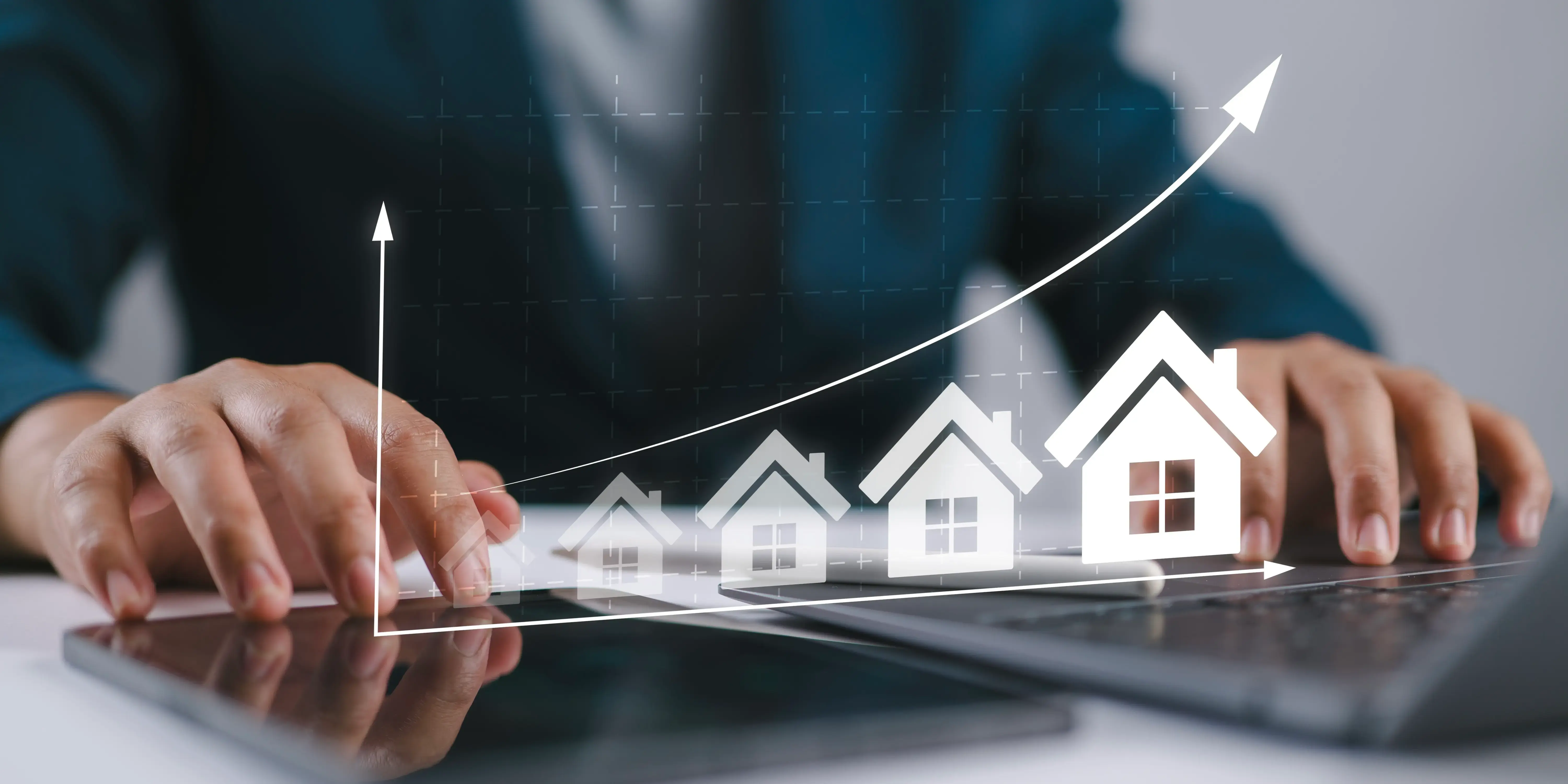 Hombre escribiendo en el teclado de la tableta con los iconos y el gráfico de la casa en ascenso, que simbolizan el crecimiento del mercado inmobiliario y cómo la plusvalía afecta la vivienda