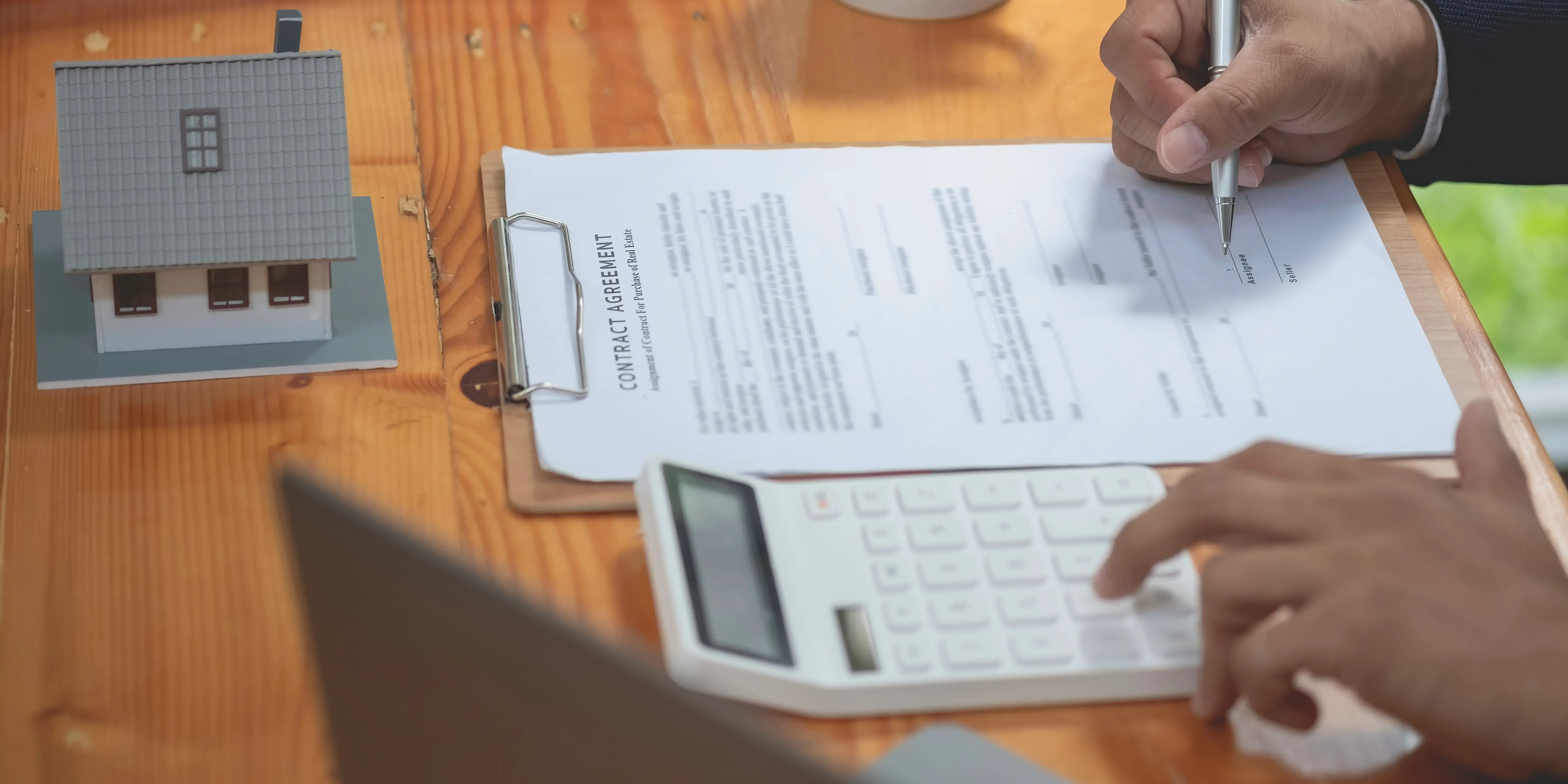 Hombre sacando cuentas en una calculadora para calcular los gastos adicionales y firmar el contrato de compraventa para comprar casa