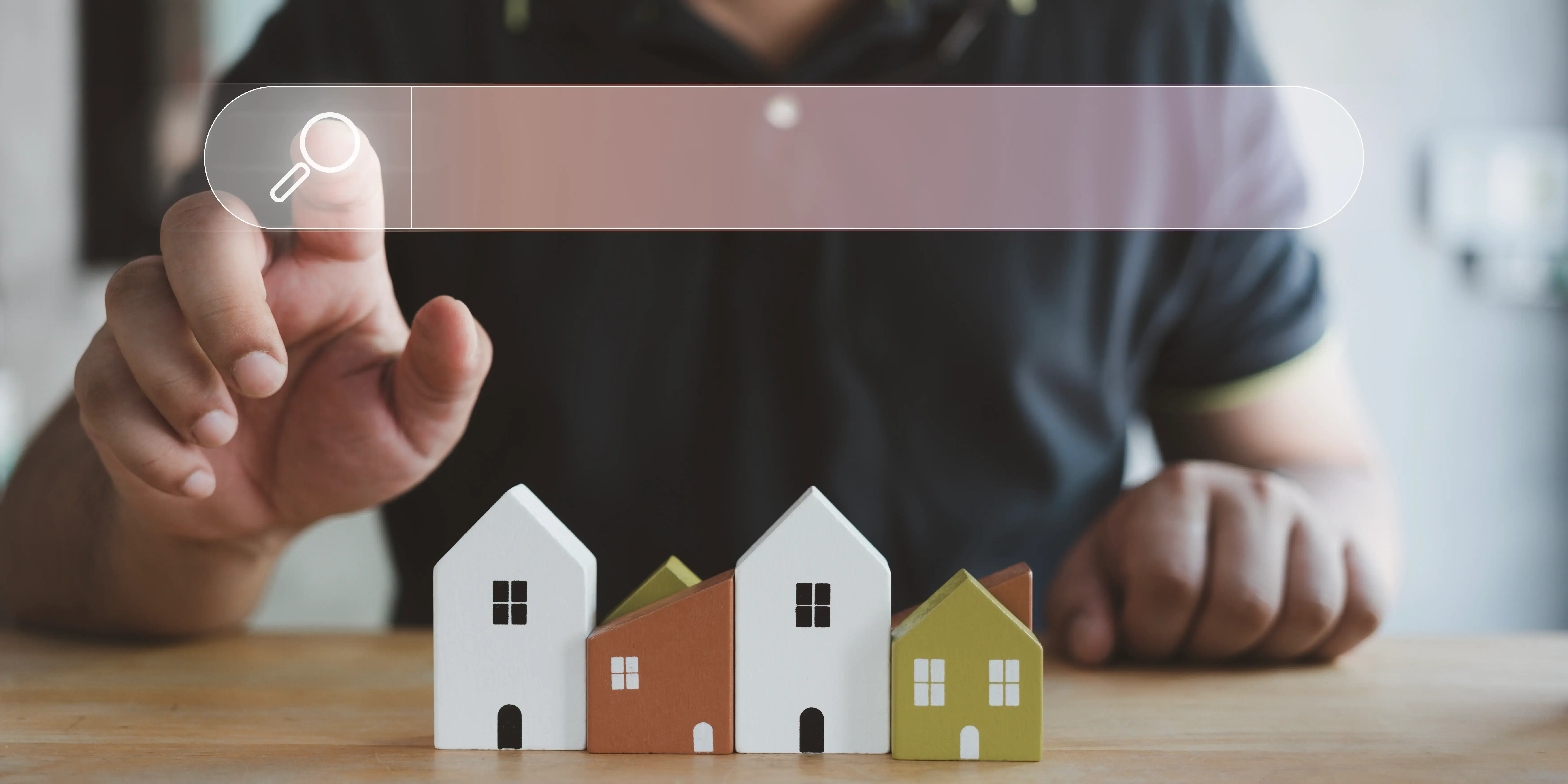La mano de un hombre tocando el icono de la lupa buscando información sobre desarrolladores inmobiliarios para comprar casa