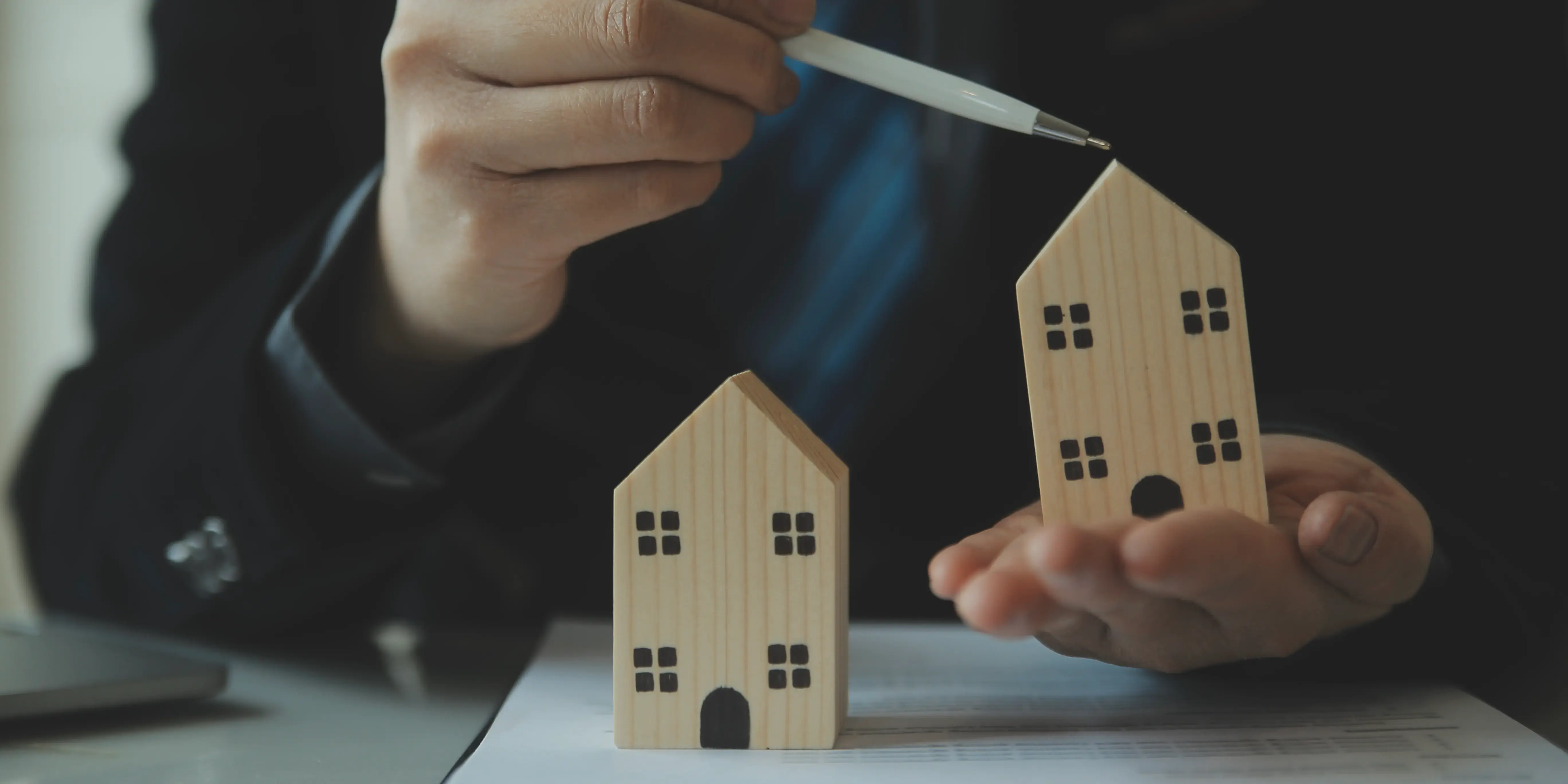 Mujer sosteniendo dos casas de madera para comprar Infonavit vs crédito hipotecario