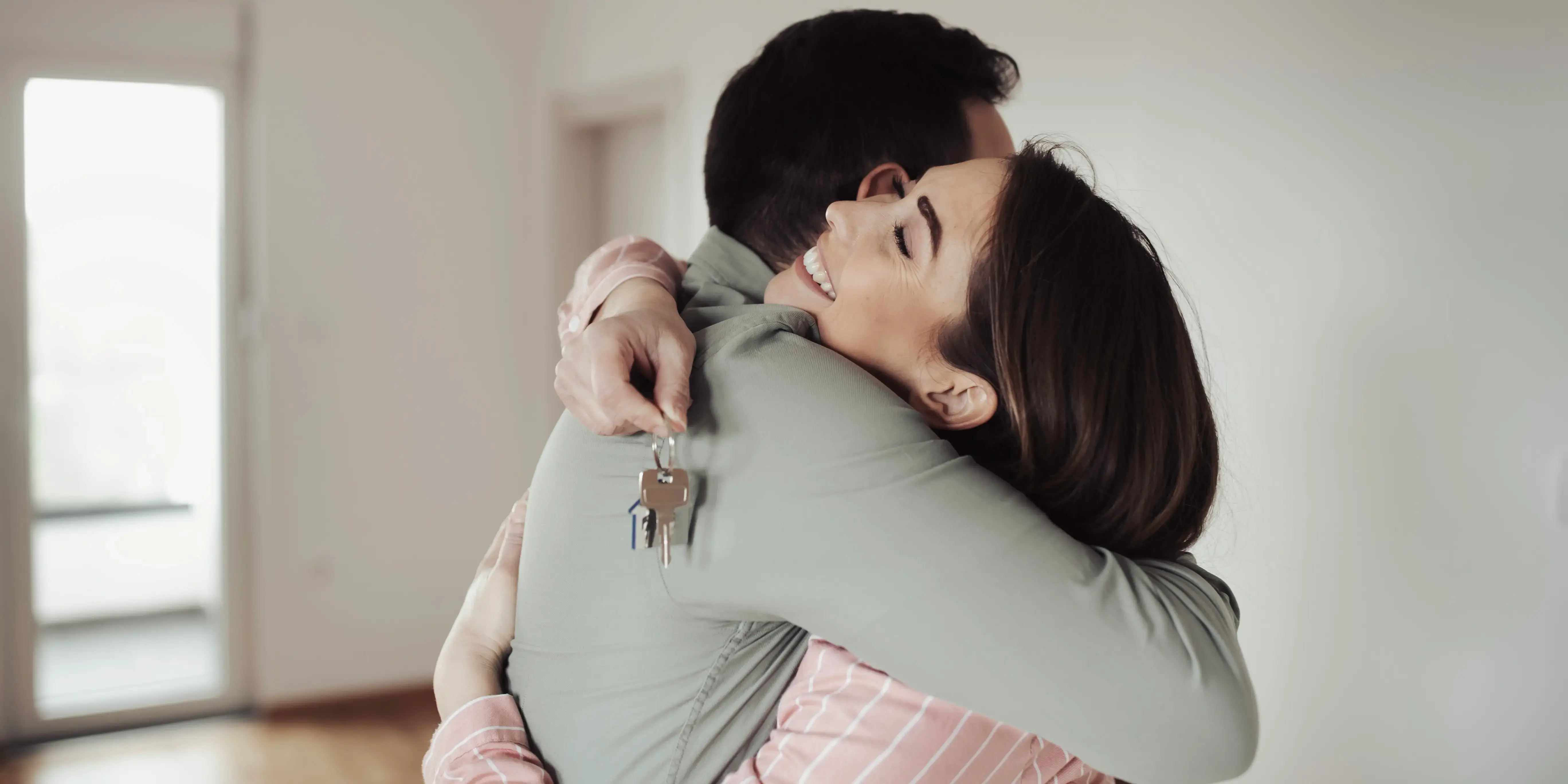 Pareja abrazándose y sosteniendo unas llaves estrenando casa usando el crédito conyugal FOVISSSTE
