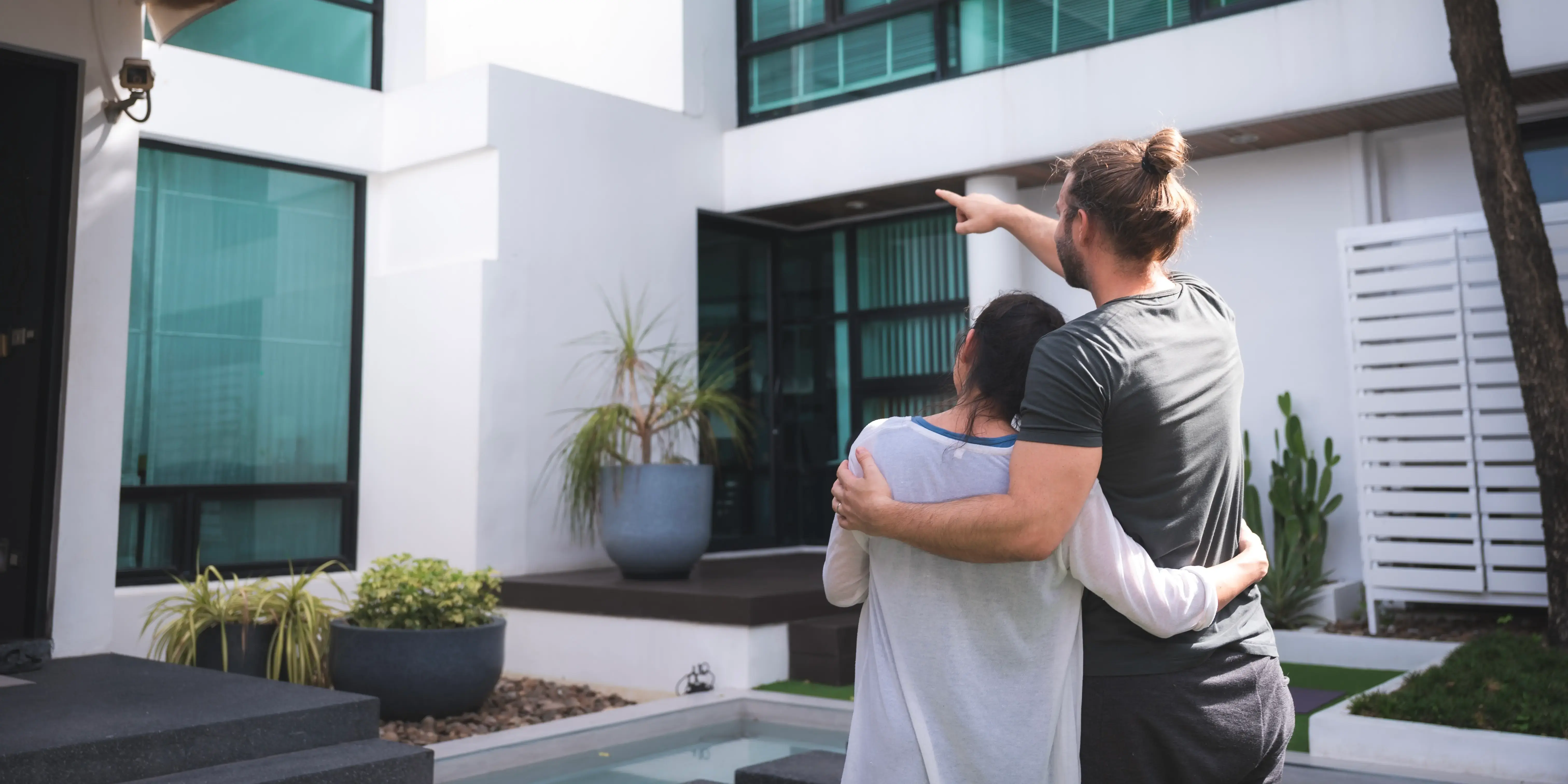 Pareja señalando una casa que les gusta despues de visitar un desarrollo para comprar una casa