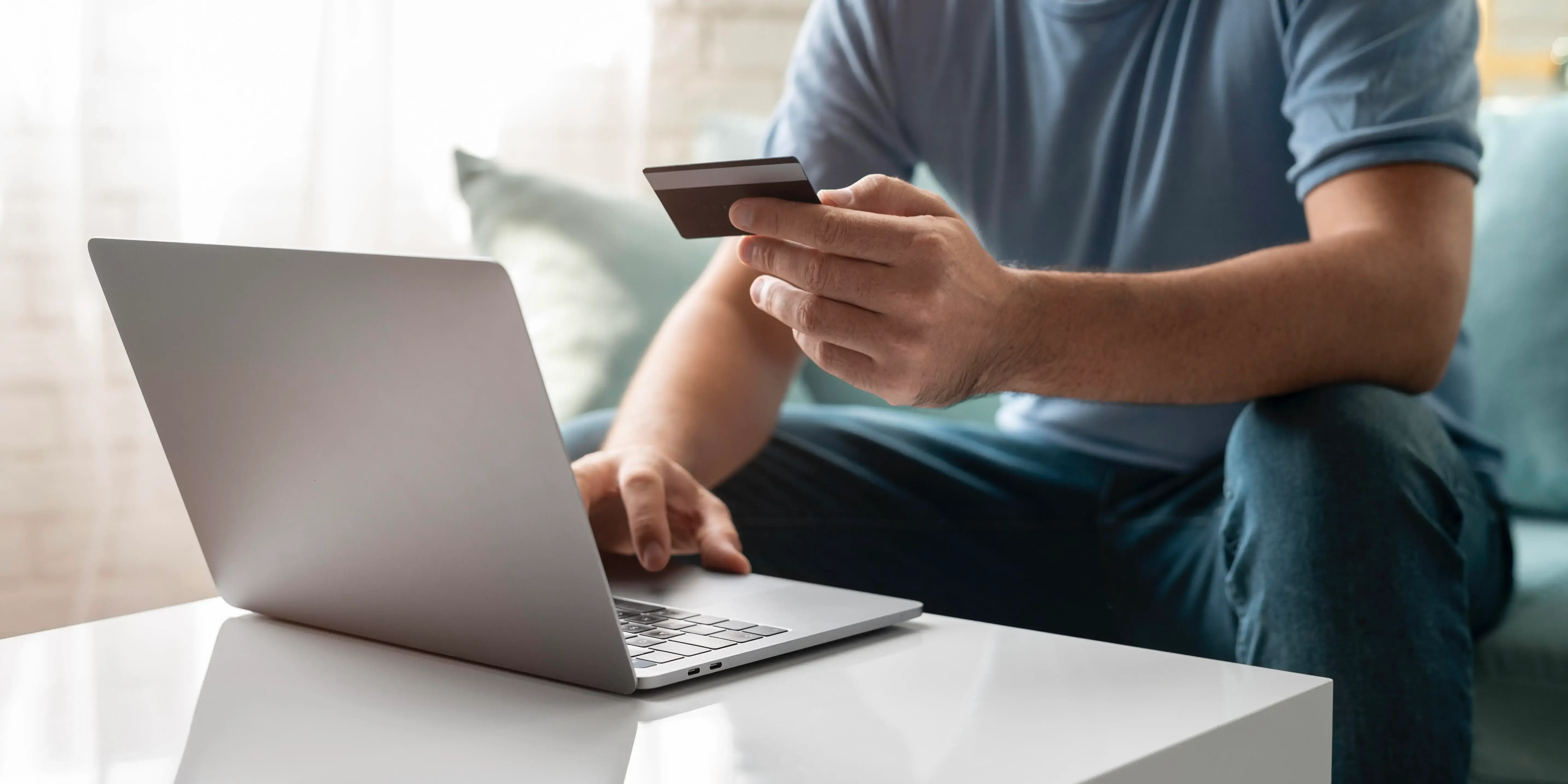 Hombre en computadora con tarjeta de crédito. Banorte en línea para comprar tu hogar