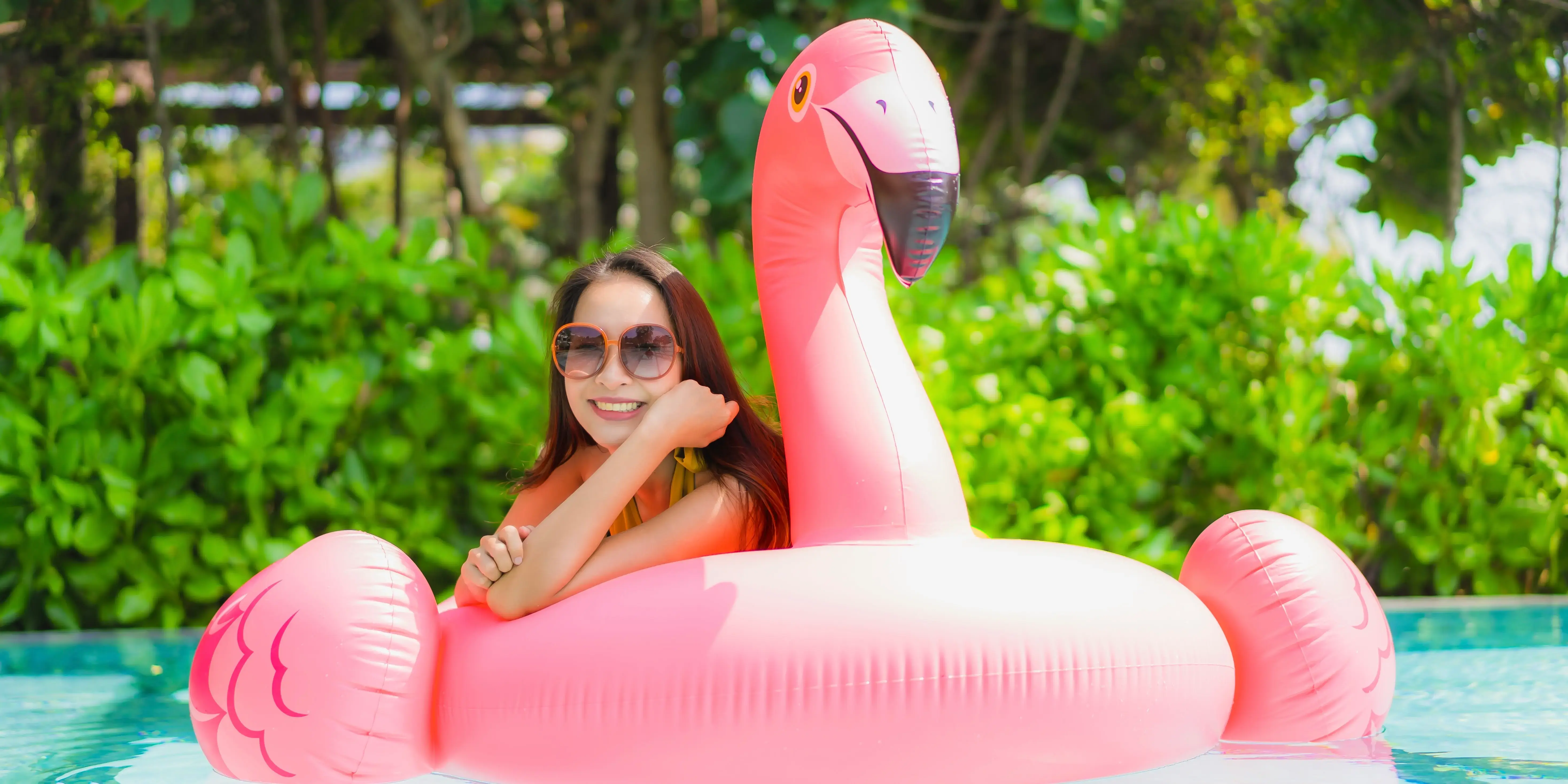 Mujer en alberca con flamingo inflable. Enamórate de las amenidades