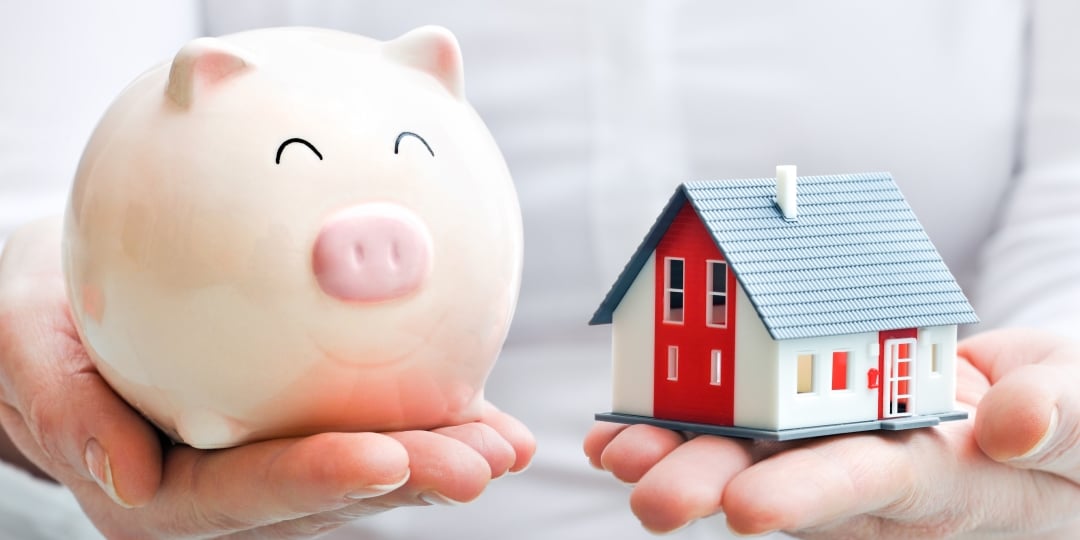 Manos sostienen una alcancía y una casa de juguete. Diferencias entre créditos en VSM y en pesos.