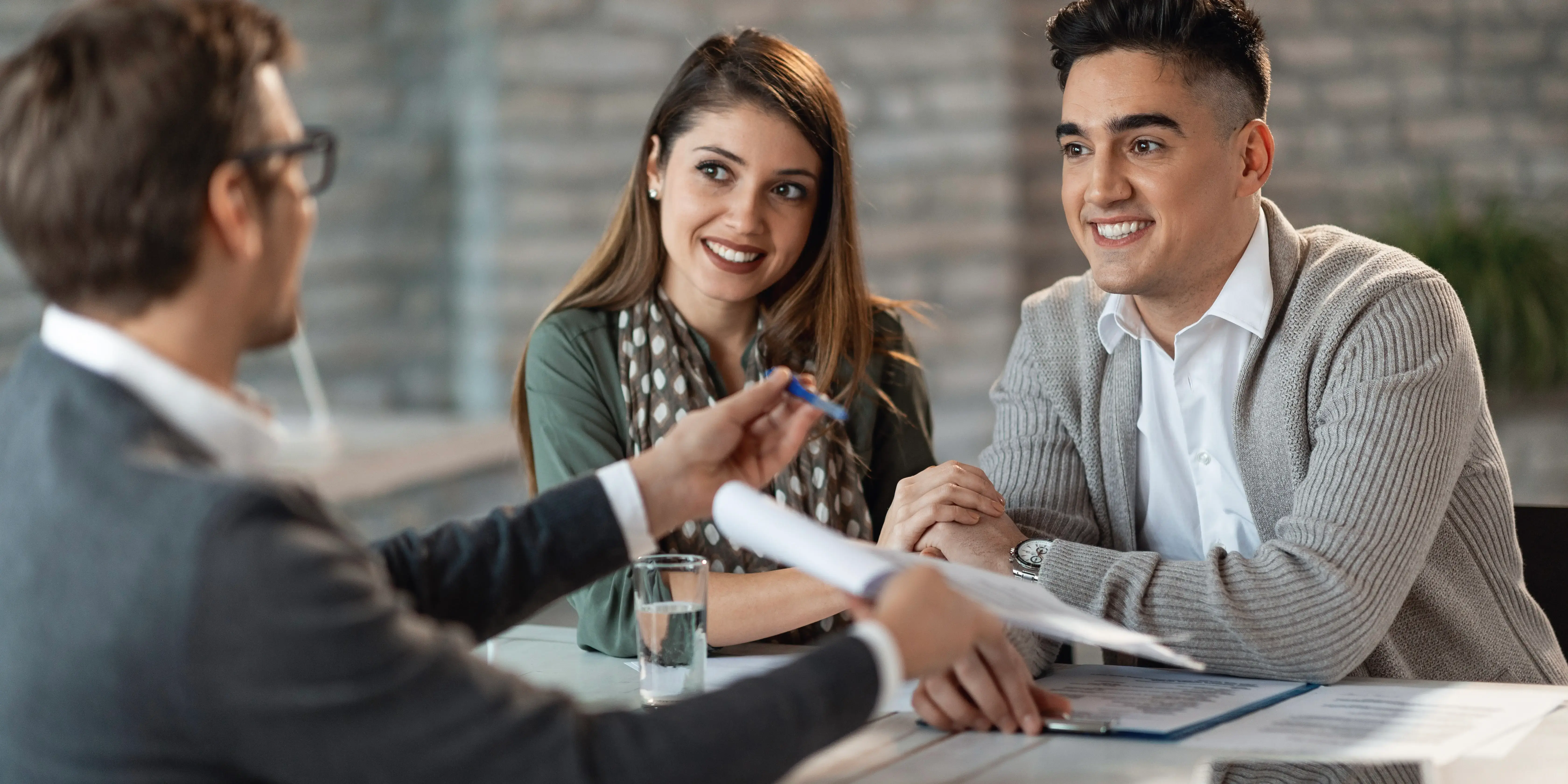 Agente inmobiliario señalando contrato a pareja. Políticas de cancelación