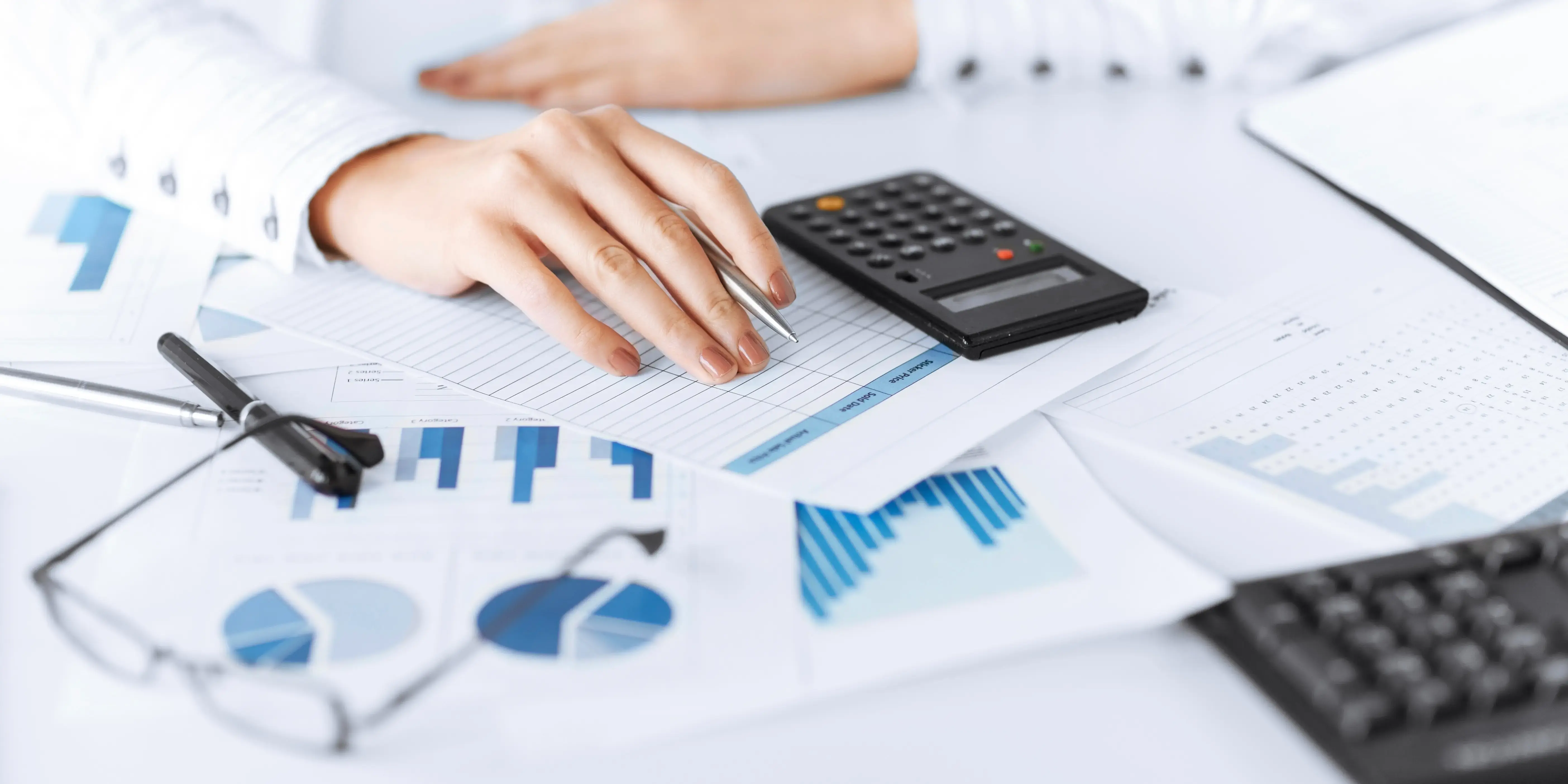 manos con hojas con gráficas y calculadora. Impuesto sobre nómina