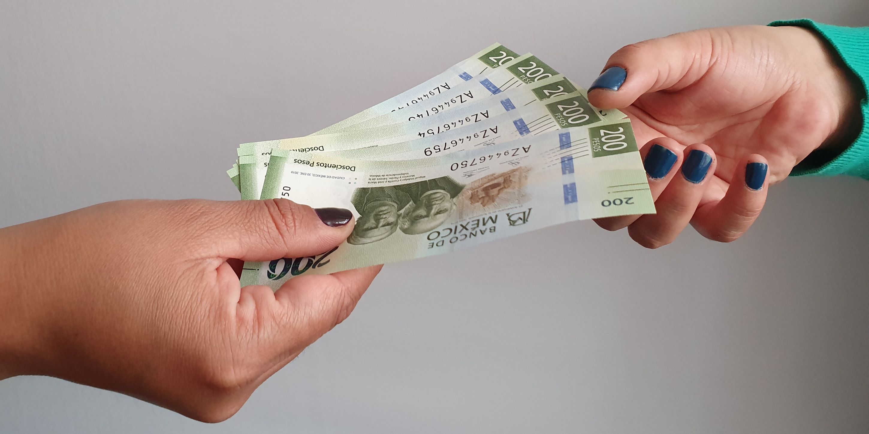 Préstamo de dinero. Una mano da un manojo de billetes a otra. Es para una compra de una casa.