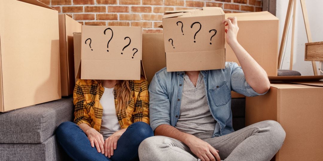 Pareja joven con cajas en la cabeza, no saben cómo hacer su mudanza de manera eficiente.