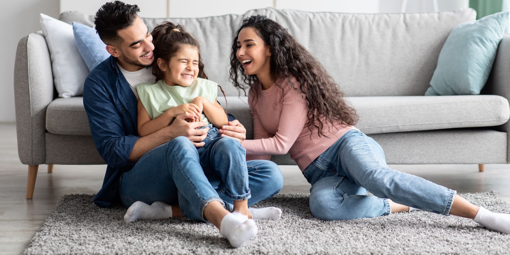 Familia joven juega en la sala de su casa. Celebran por el Día de la Familia.