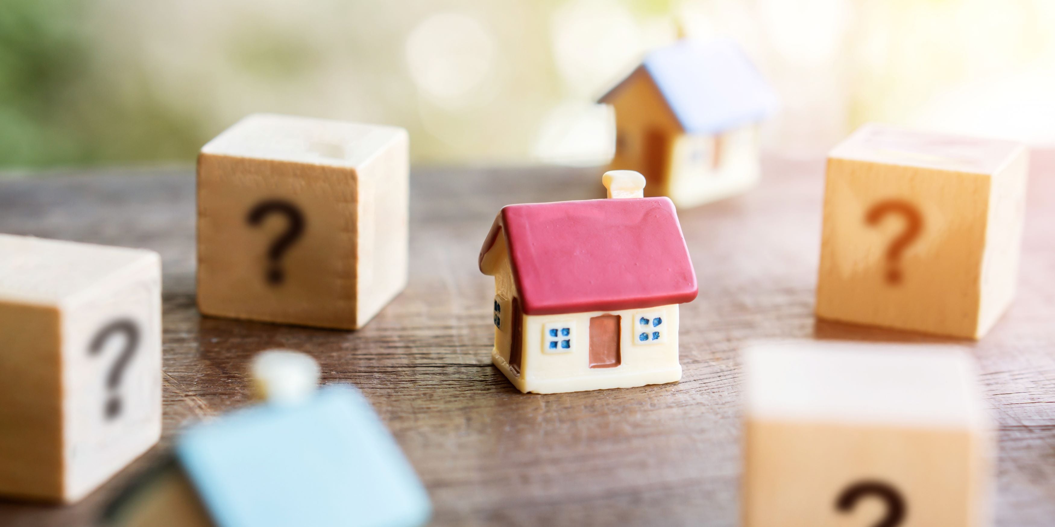 La evolución de los precios de vivienda en México. Casas y cubos con signos de interrogación que representa la incertidumbre en precios de casas.