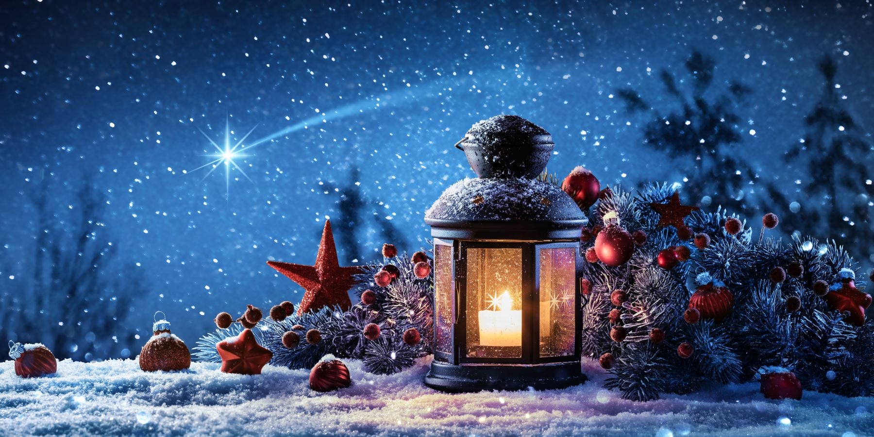 Un candelabro en medio de la nieve. Hay adornos navideños al rededor y una estrella que simboliza a Belén.