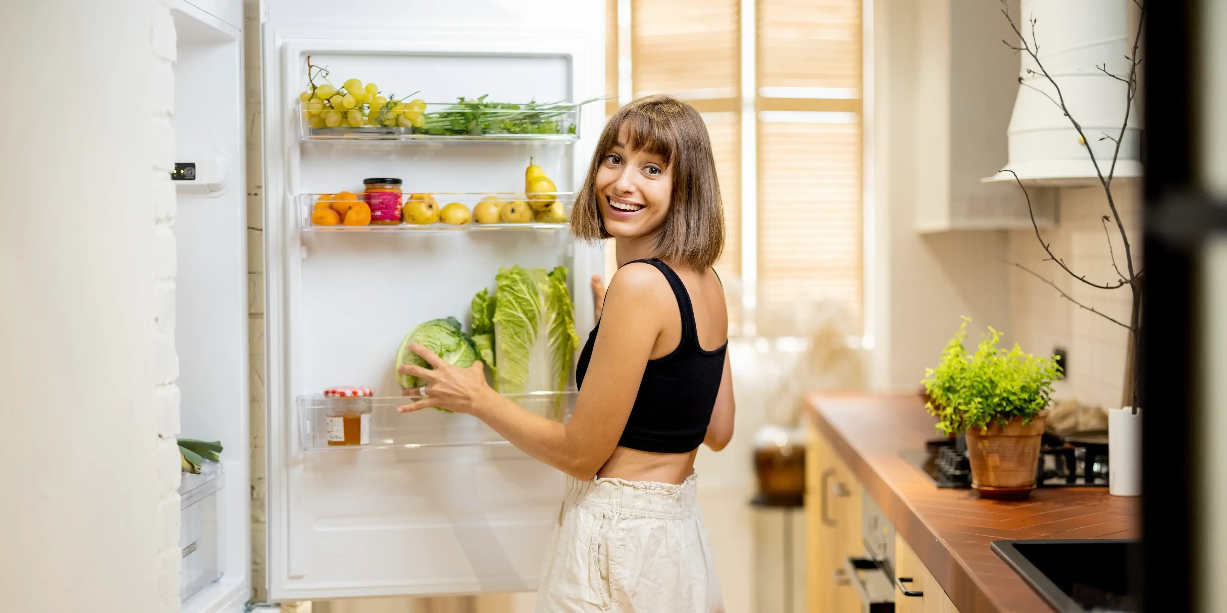 Mujer joven guardando la comida en el refrigerador cuando vive solo.