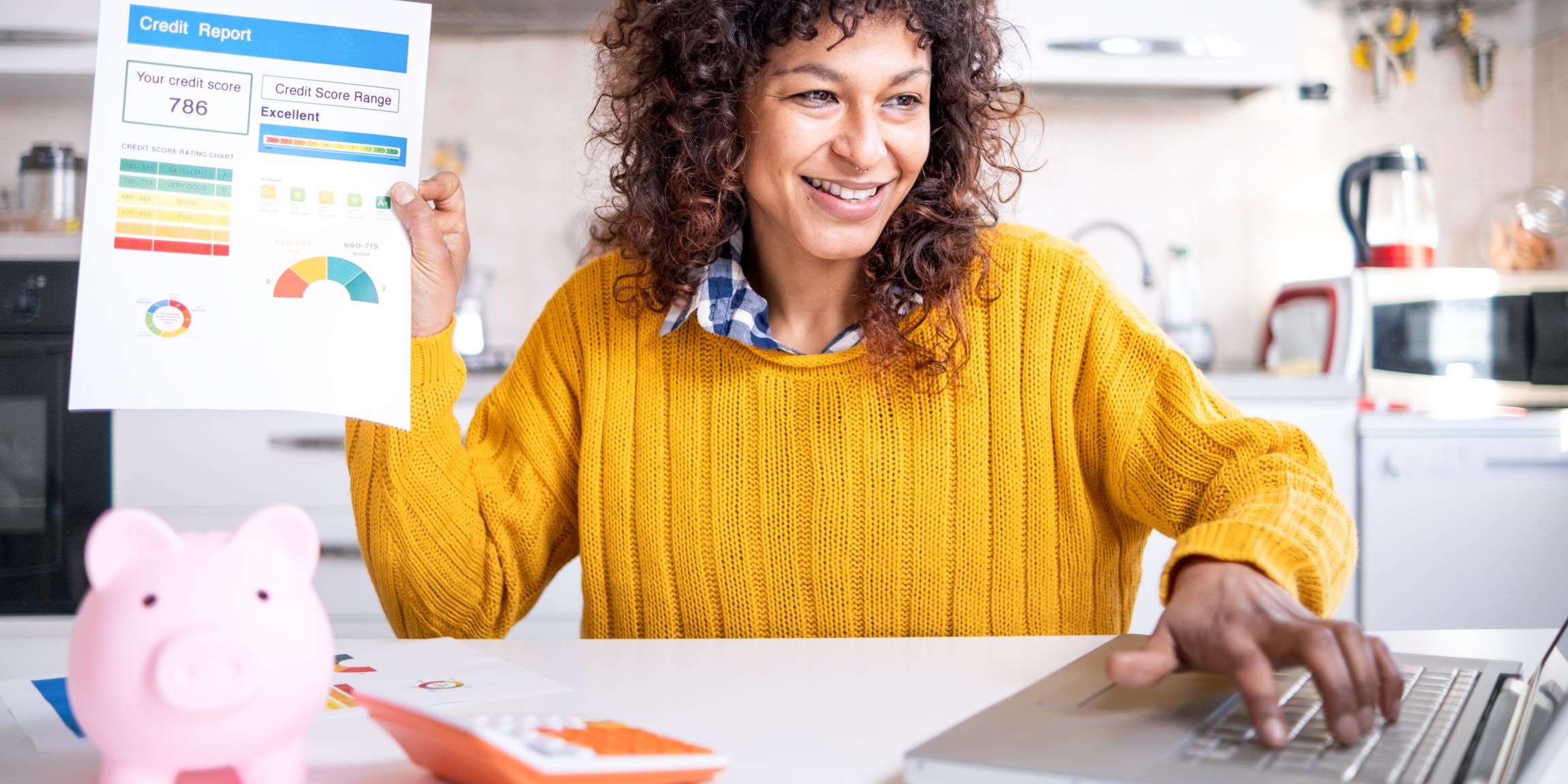 Mujer con su estado crediticio, un cochinito de ahorro y una lap top checando que todo esté bien para comprar una casa.