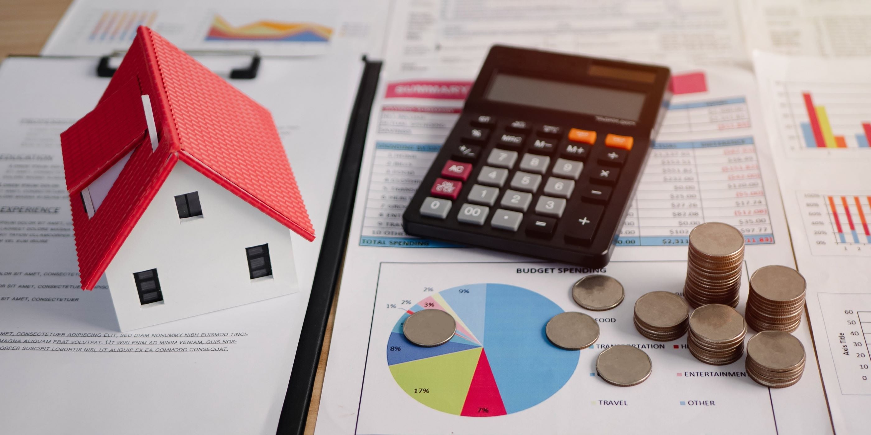 Impuesto sobre la compra de una vivienda. Casa miniatura sobre hojas con datos estadísticos, al lado una calculadora y monedas.