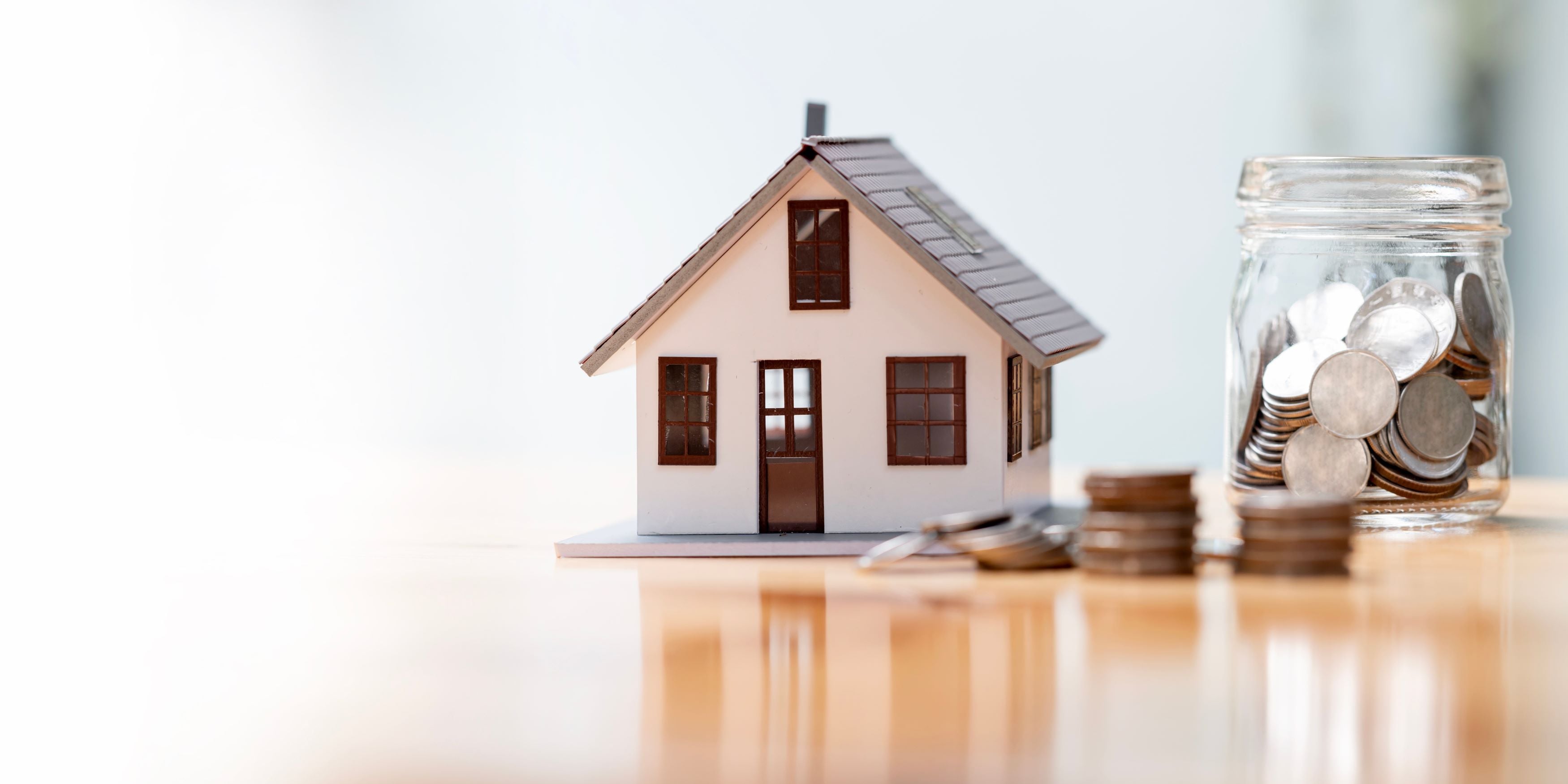 Fonacot: ¿Qué es y cómo funciona? Casita miniatura con un frasco lleno de monedas.