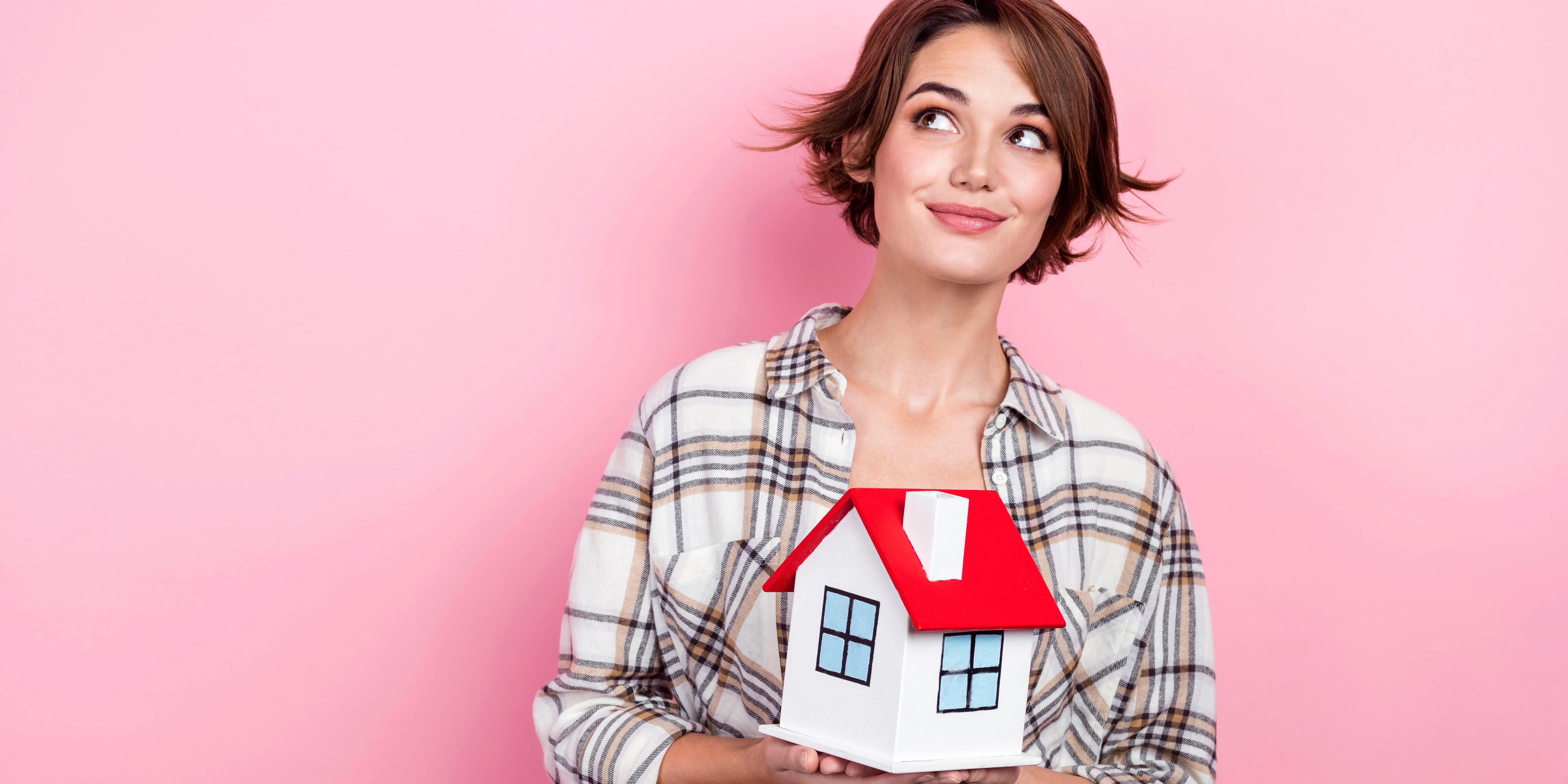 Mujer sosteniendo una casa de madera preguntándose si conviene comprar una casa en preventa