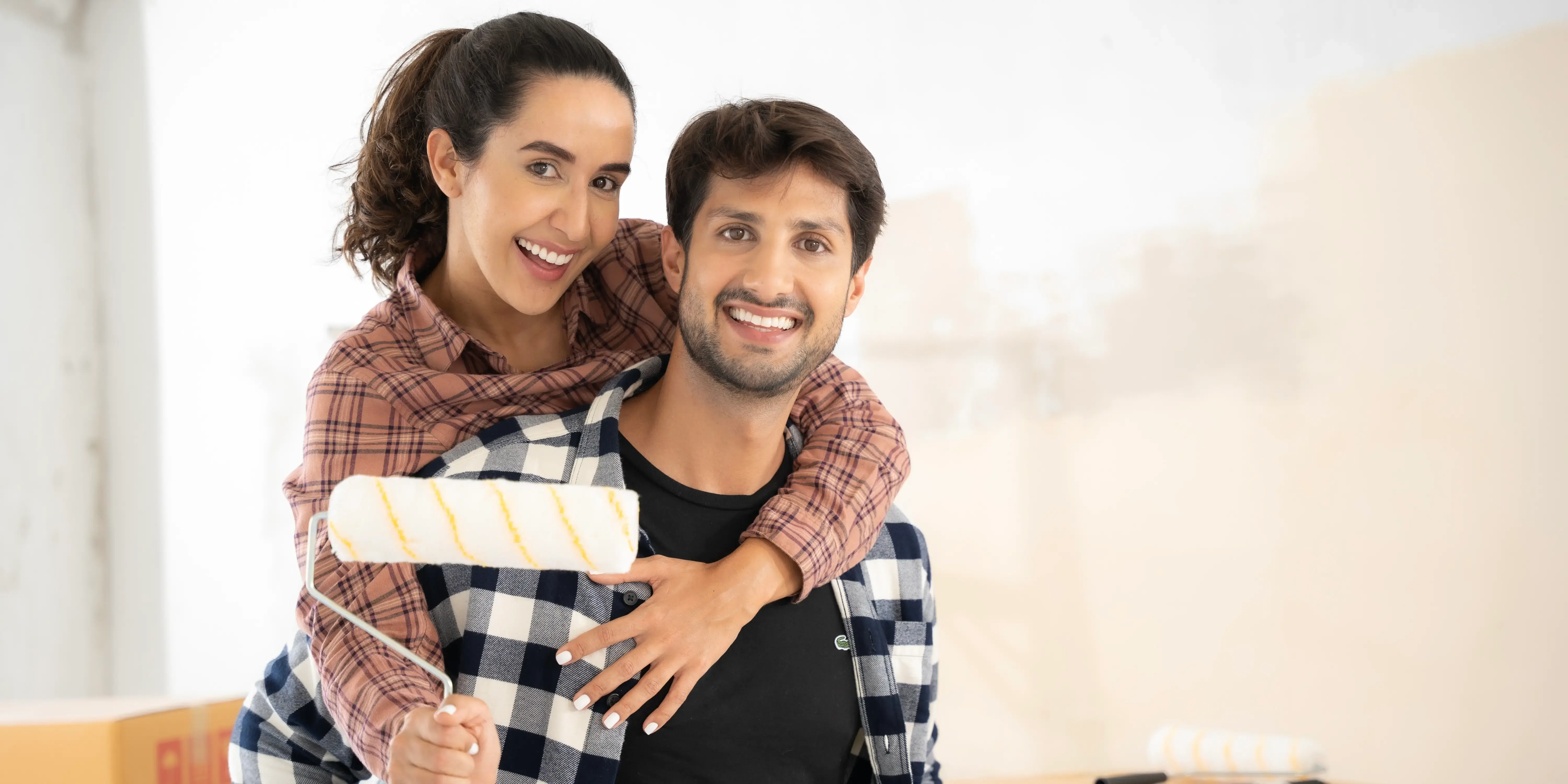 Pareja con rodillo para pintar paredes. Remodelar tu casa