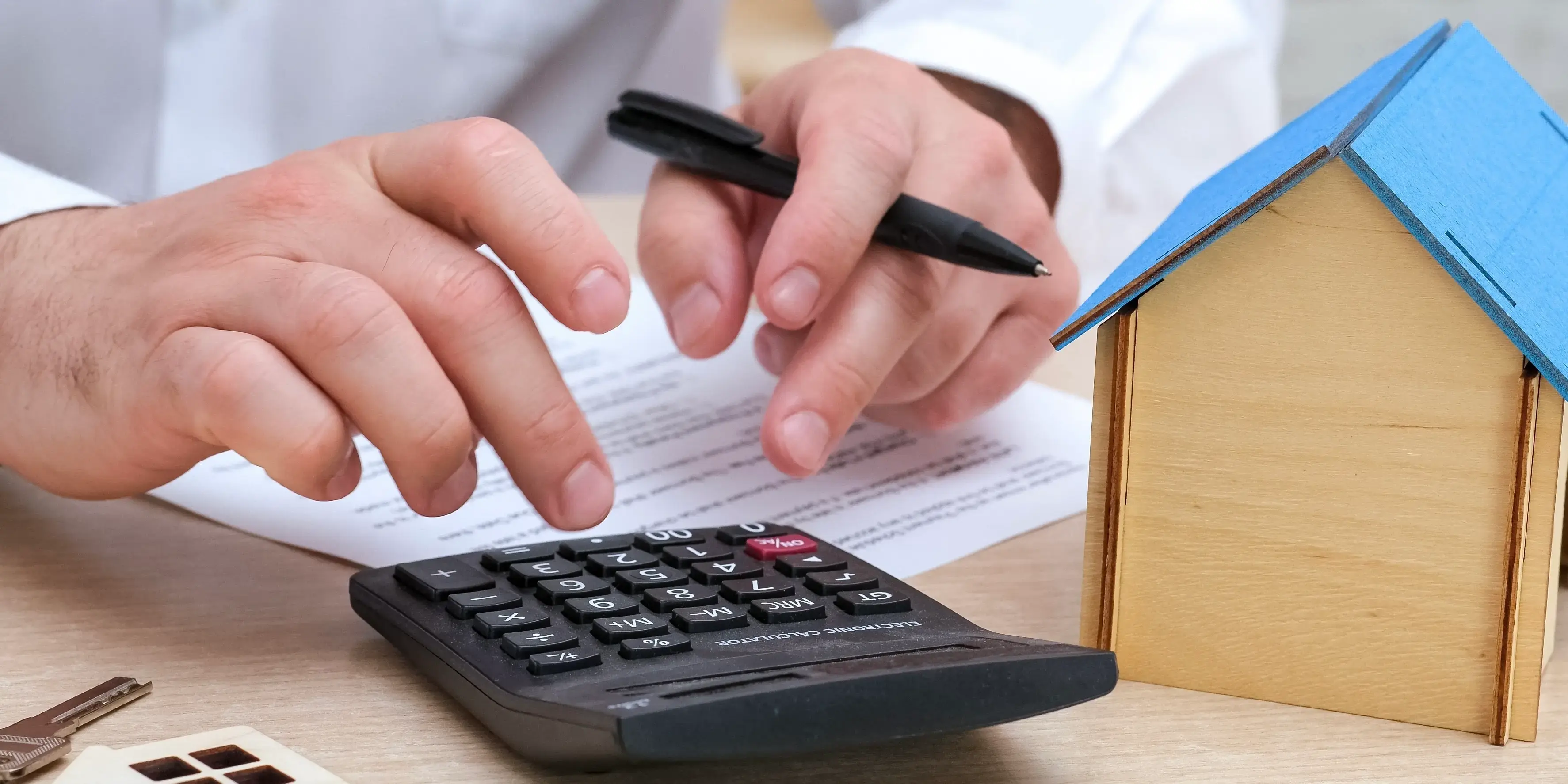 Hombre con calculadora, documentos y una casa. Preaprobado