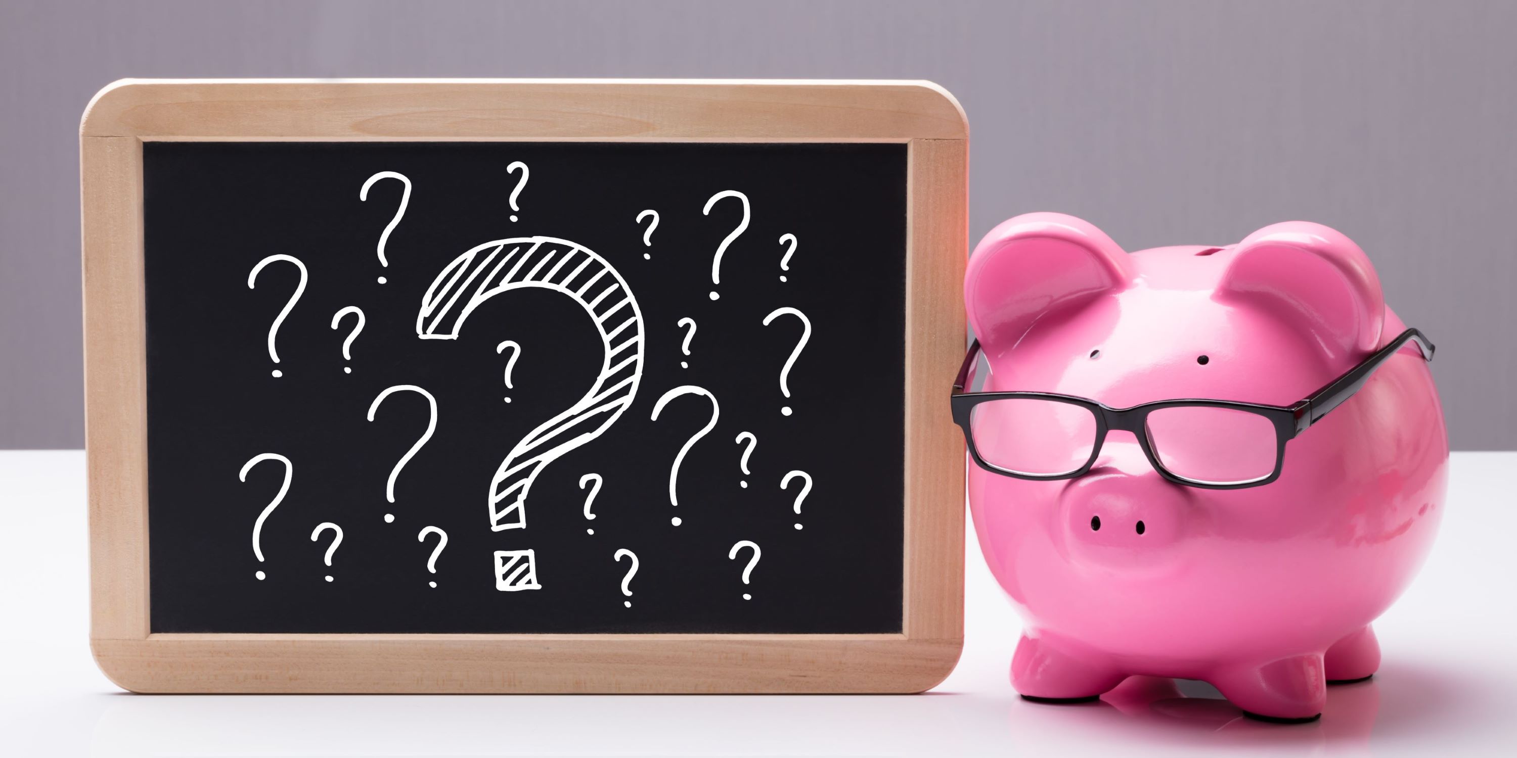 ¿Cuánto dinero puedo obtener con mi primer crédito Infonavit? Cochinito de porcelana al lado de un pizarrón con signos de interrogación.