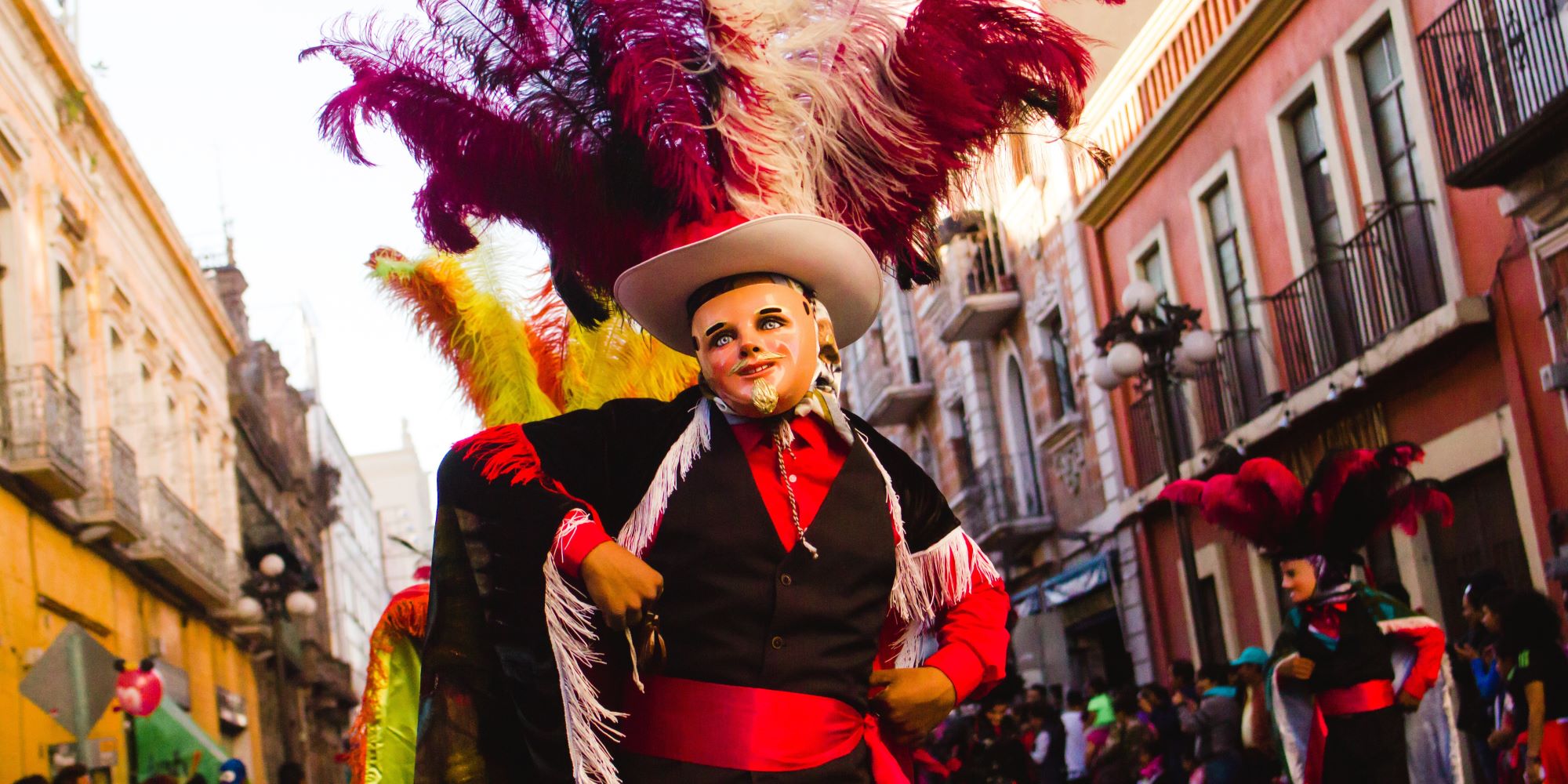 Huehue bailando un baile tradicional de Hidalgo. Máscara de viejito, con plumaje y vestimenta roja y negra formal.