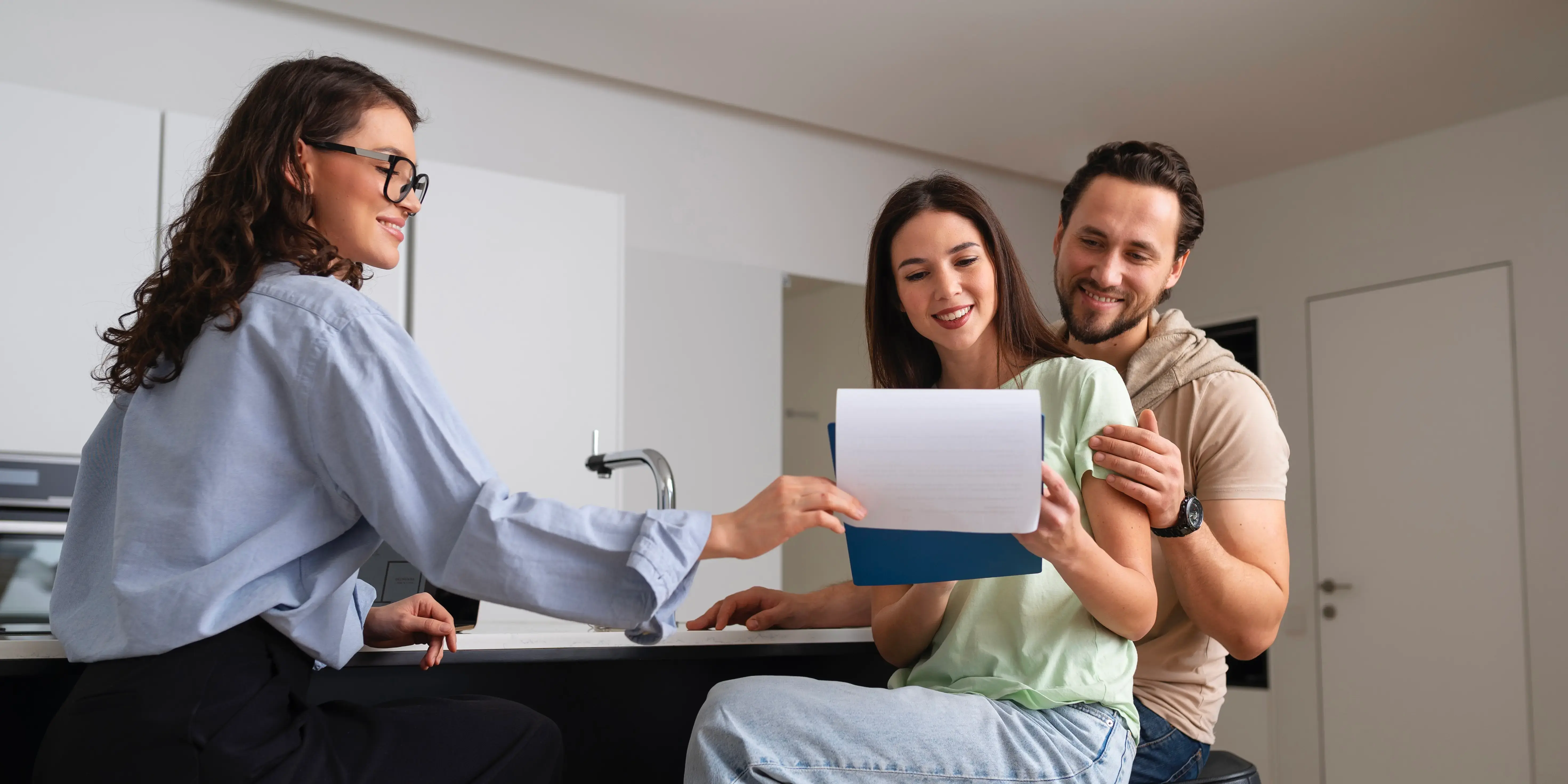 Bróker enseñándole papeles a una pareja. Propósito de comprar casa.